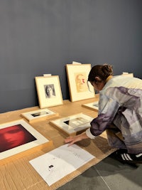 a woman looking at framed photographs on a table